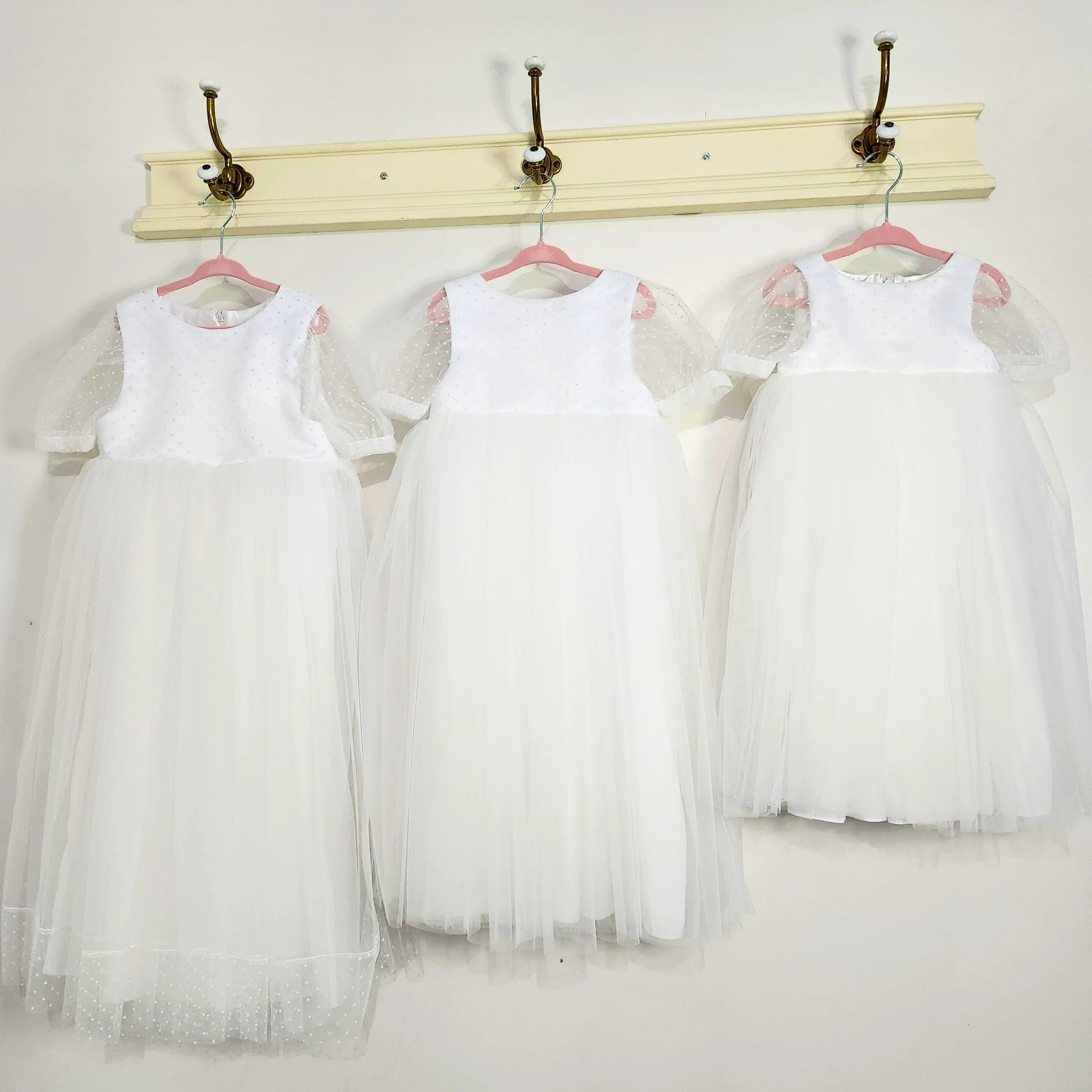 three White flower girl Dresses hanging on a hook image 3