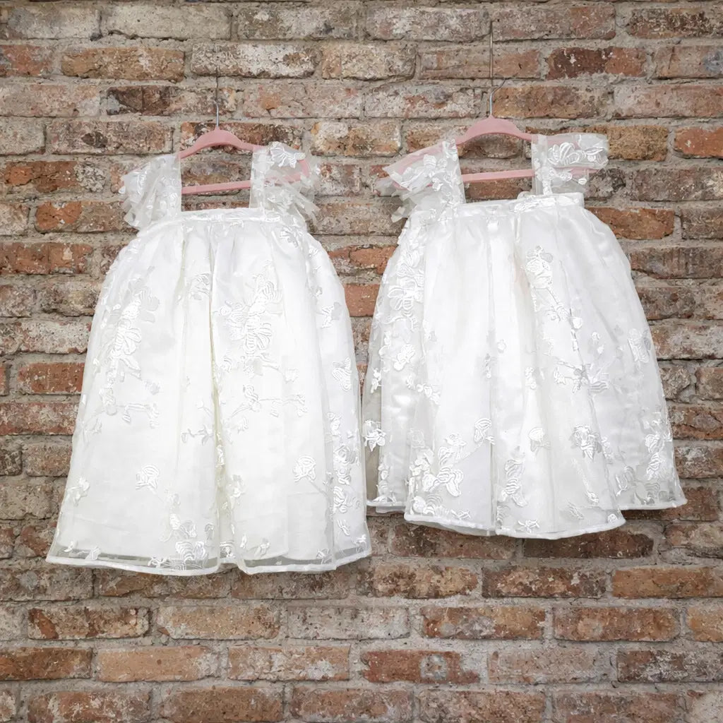 two Babydoll Flower Girl Dresses hanging against a brickwall image 8