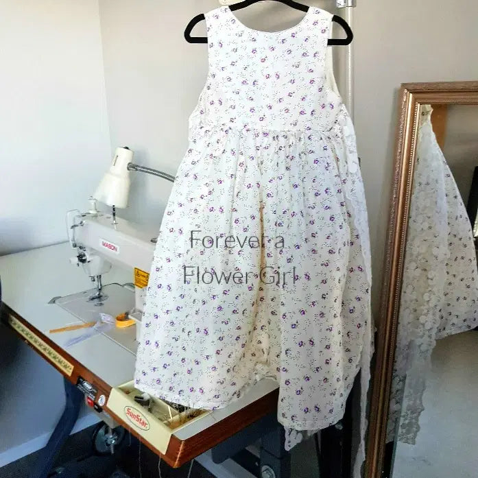 purple Floral Cotton flower girl dress  hanging beside a sewing machine image 3