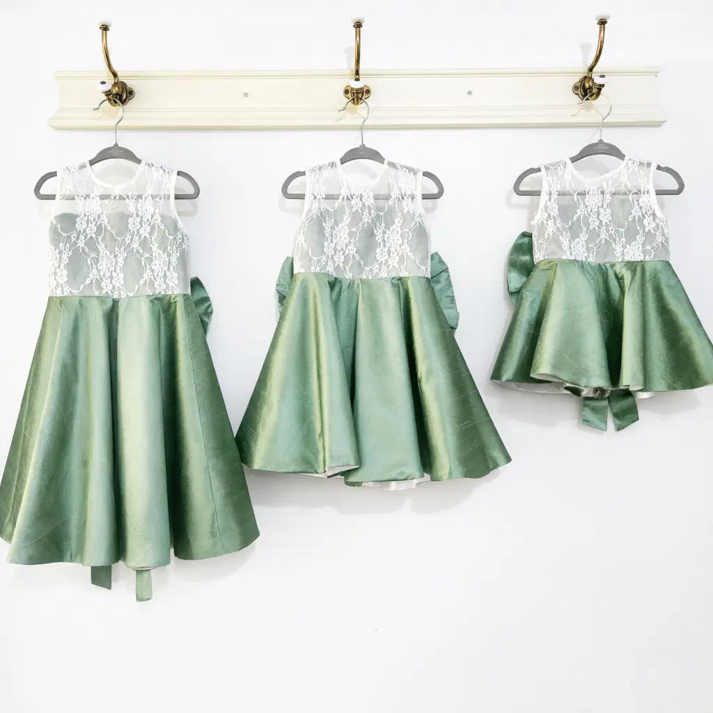 three Sage Green Flower Girl Dresses with lace hanging on a hook image 5